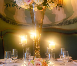 Elegant round table with glassware, plates, menus, floral centerpiece, and candles—ideal for a Gulf South wedding reception.