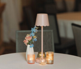 Elegant round table with white cloth, pink lamp, pastel flowers, and lit candles—ideal for a New Orleans wedding.