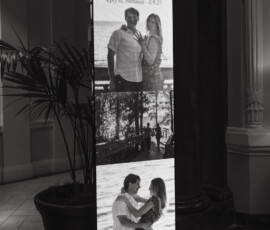 Digital screen with three black-and-white engagement photos and “Congratulations: Rory & Brennan - 8.9.23” in indoor venue.