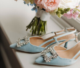 Light blue jeweled heels in front of a pink, white, and blue bouquet on a windowsill—chic Gulf South wedding inspiration.
