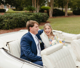 Bride and groom laughing in a white convertible with bouquet, surrounded by greenery—Louisiana wedding inspiration.