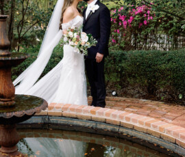 Bride and groom kiss by a brick path and pond in a lush garden, inspiring Gulf South wedding ideas.