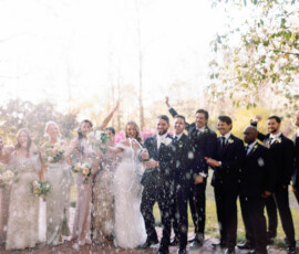 Outdoor wedding party cheer as champagne pops, guests dressed formally and smiling, capturing New Orleans celebration spirit.
