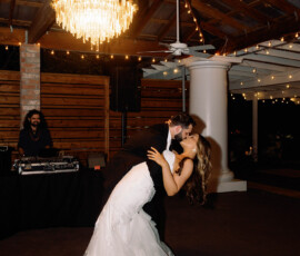 Bride and groom smile while dancing under a chandelier at their Louisiana wedding, with twinkle lights and DJ in the background.