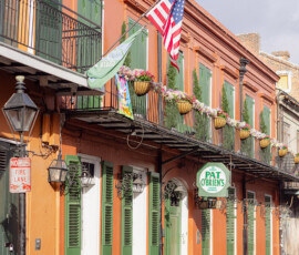 Pat O’Brien’s historic French Quarter building with green shutters, potted plants, flags, and charming wedding backdrop.