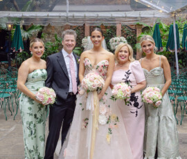 Wedding party of five under a clear tent; bride in white floral gown, others in formal attire with bouquets and lush New Orleans backdrop.