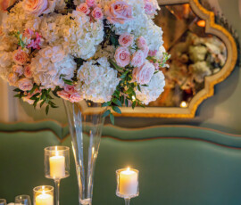Elegant dining table with white and pink flower centerpiece, candles, glassware, mirror, and green wall—Louisiana wedding.