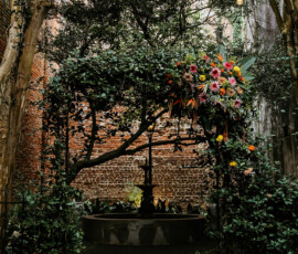 Colorful flower archway with hanging lights in a lush Louisiana garden, perfect for dreamy wedding inspiration.