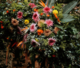 Colorful floral arrangement with chrysanthemums and birds of paradise, set outdoors by a brick wall—ideal Gulf South wedding decor.