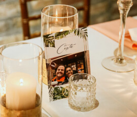 Decorated table with candles, glass vase, and Costa postcard of two smiling people at a New Orleans wedding.