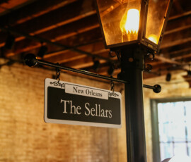 Indoor streetlamp with “New Orleans The Sellars” sign, brick wall, and wood beams creates a charming wedding venue ambiance.