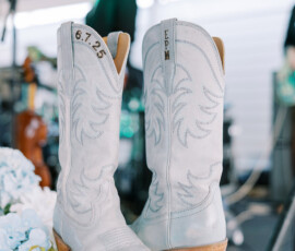 Light blue cowboy boots with 6.7.25 and EPM, displayed with a bouquet and musician, capturing New Orleans wedding vibes.
