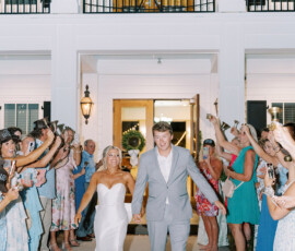 Bride and groom walk hand in hand outside as guests cheer and take photos during their joyful New Orleans wedding.