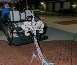 Just Married golf cart with tin cans and ribbons drives at night on a brick path, perfect for a New Orleans wedding.