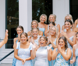 “Bridesmaids in light blue dresses cheer and smile with excitement during a first look moment at an outdoor wedding venue.”