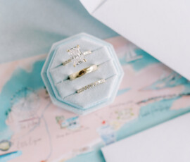 Gold rectangular diamond engagement ring and wedding band in blue velvet box on illustrated map, ideal for Louisiana weddings.