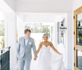 Bride in a strapless white gown and groom in light gray suit walk hand-in-hand, smiling at their New Orleans wedding.