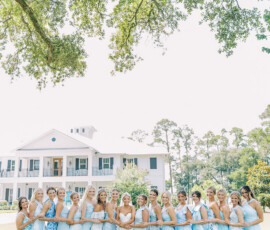 Women in light blue dresses stand on a lawn by a white house, offering classic Louisiana wedding inspiration.