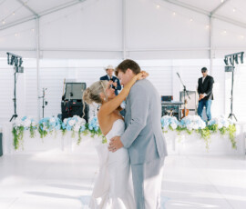 Bride and groom share their first dance under a white tent with blue flowers at a New Orleans wedding.