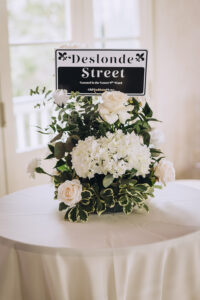 White rose and hydrangea centerpiece with a Deslonde Street sign, perfect for an elegant Louisiana wedding reception.