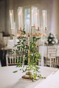 Gold candelabra with glass holders and green vines on a round table—ideal for an elegant Louisiana wedding.