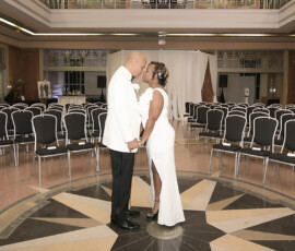 Bride and groom hold hands in an elegant, empty hall with black chairs and a star-patterned floor, Gulf South wedding inspiration.