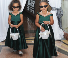 Two flower girls in green dresses and sunglasses walk down a New Orleans wedding aisle, each holding a white basket.