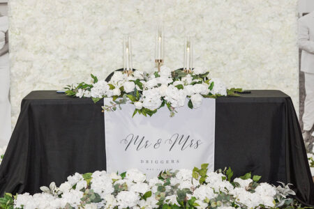 Elegant Louisiana wedding setup: black table, white flowers, greenery, candles, and “Mr & Mrs Driggers” sign, May 11, 2022.