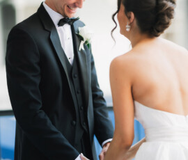 Bride and groom smile and hold hands in a joyful, intimate Gulf South wedding, she in a strapless dress, he in a tuxedo.