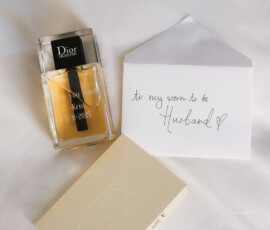 Dior Homme cologne, a “to: my soon to be Husband ♥” envelope, and GROOM card on white surface—Gulf South wedding details.
