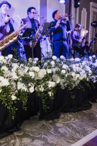 A band plays saxophones and sings on stage with white flowers, creating classic Louisiana wedding inspiration.