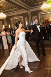 Bride and groom dancing at their Louisiana wedding reception, with guests in a chandelier-lit ballroom.