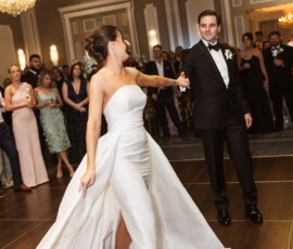 Bride and groom dancing at their Louisiana wedding reception, with guests in a chandelier-lit ballroom.
