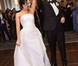 Bride in white strapless gown and groom in black tuxedo twirl during their first dance at a Louisiana wedding reception.