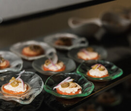 Appetizers with olives, red onions, and creamy spread in glass dishes on black shelves—chic Louisiana wedding inspiration.