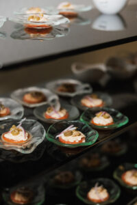 Appetizers with olives, red onions, and creamy spread in glass dishes on black shelves—chic Louisiana wedding inspiration.