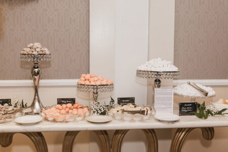 Elegant dessert table with pastel macarons, powdered treats, and candies on glass stands—ideal for Gulf South weddings.