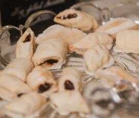 Rolled cookies with dark filling on a glass platter, served with tongs—ideal for a Louisiana or New Orleans wedding.