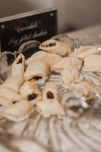 Rolled cookies with dark filling on a glass platter, served with tongs—ideal for a Louisiana or New Orleans wedding.