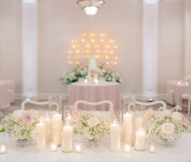 Louisiana wedding reception with white chairs, blush and white florals, candles, a tiered cake, and string lights.