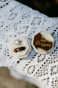 Diamond and wooden rings in a cream box beside engraved gold box on lace—elegant Louisiana wedding detail.