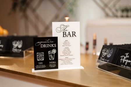 Louisiana wedding bar menu with His and Hers cocktails, black napkins, and a gold countertop for an elegant reception.