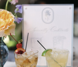 Signature cocktails displayed with garnishes beside a custom drink menu during the wedding reception.