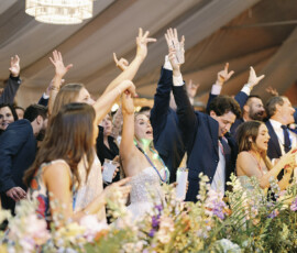 Guests dancing and celebrating under the clear-top tent as the band performs, capturing a lively wedding reception moment.