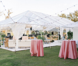 Reception lounge seating with white sofas, pastel accent pillows, and a glass coffee table topped with a floral arrangement.