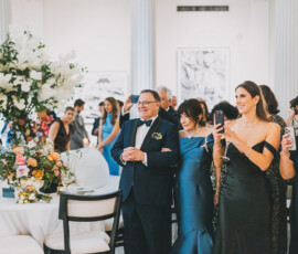 Well-dressed guests mingle and take photos by a decorated table at an elegant indoor event, inspiring Gulf South weddings.