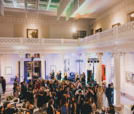 Guests in formal wear dance and mingle in an elegant hall as a live band plays at a classic New Orleans wedding reception.
