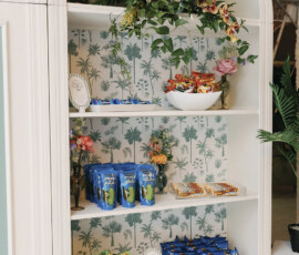 Curated snack wall featuring chips, candy, and late-night treats styled with palm-print wallpaper and floral accents.