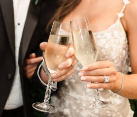 Bride and groom toast with champagne at their Orange Beach Alabama wedding, smiling in formal attire and floral dress.