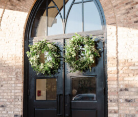 Elegant tall black double doors with arched windows and green wreaths, ideal for an Orange Beach Alabama wedding.